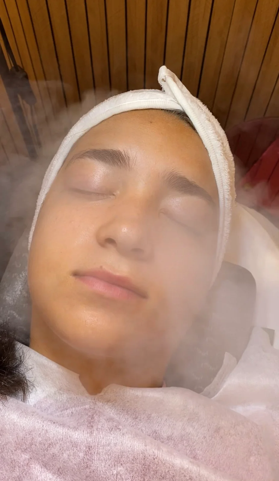 Tratamiento facial con vapor y una toalla blanca alrededor del rostro.