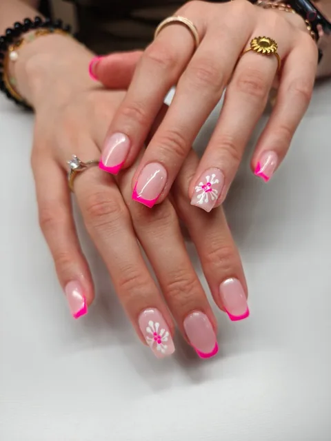 Manicura francesa fucsia con flores blancas.