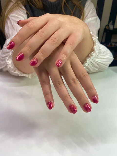 Manicura corta en rojo frambuesa con reflejos brillantes.