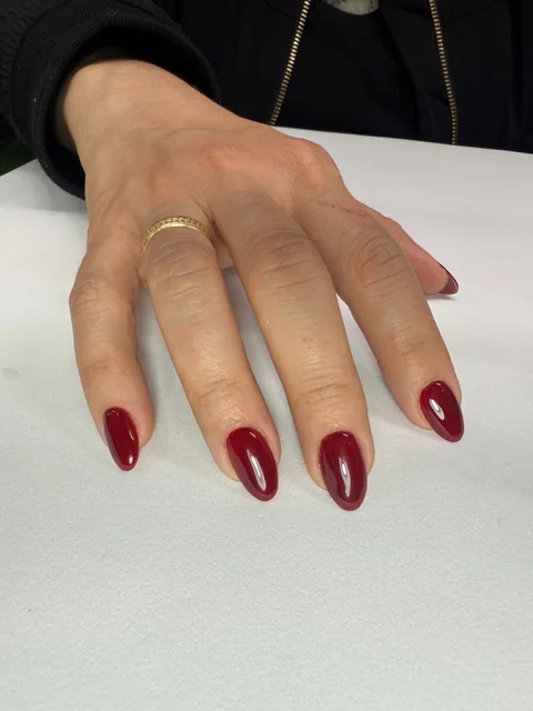Uñas almendradas con esmalte rojo intenso y brillante.
