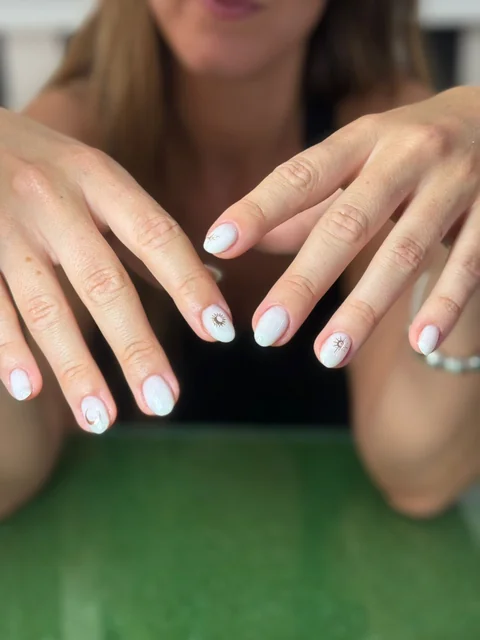 Manicura azul muy claro con motivos de sol y luna.
